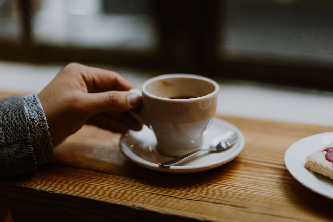hand holding a coffee mug in a cafe setting
